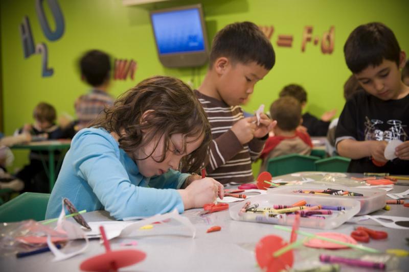 Young children in a classroom working with crayons