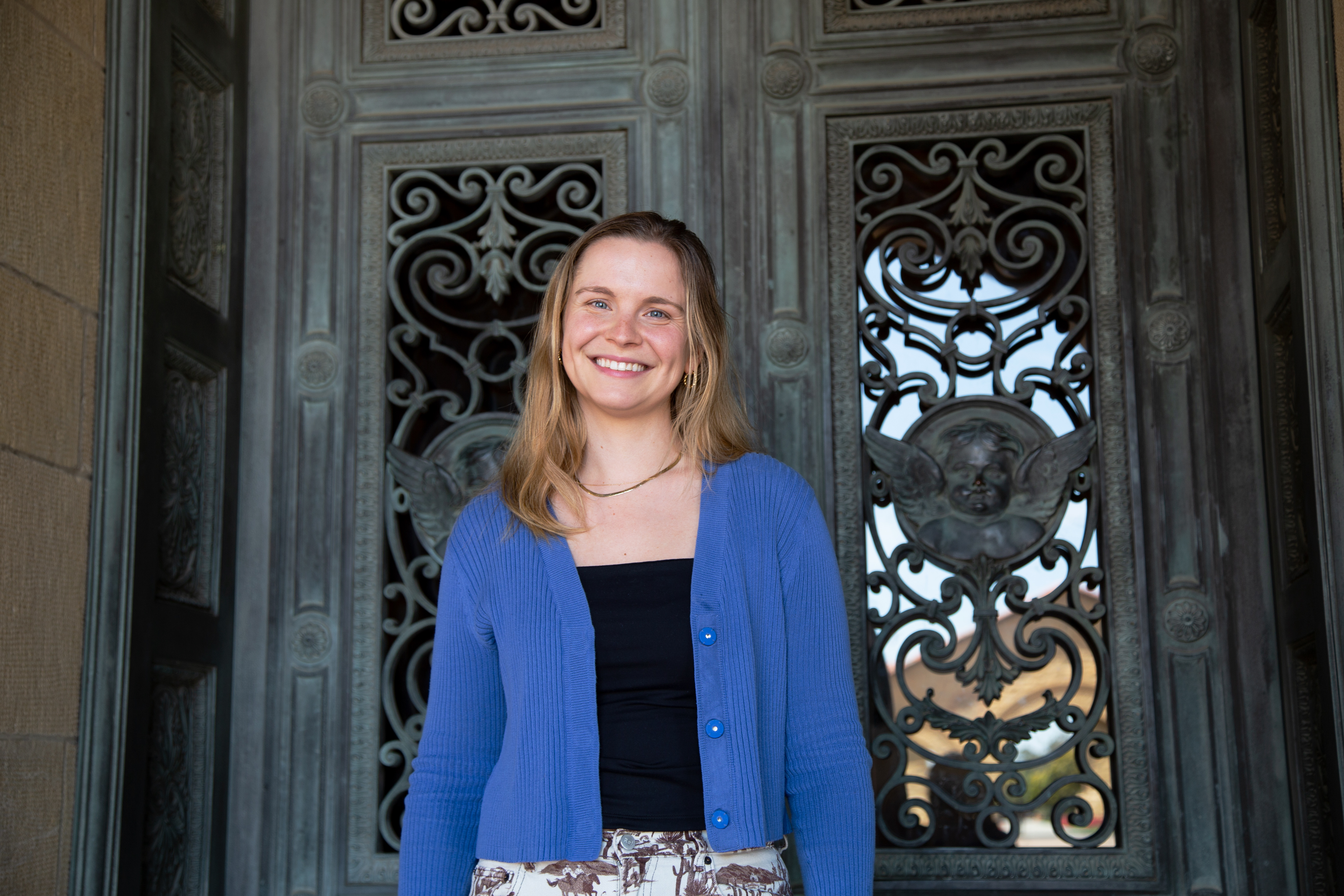 Photo of Gerta Guitart standing in front of the decorative metal doors of Memorial Church